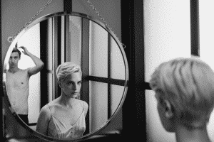un hombre y una mujer viendose en el reflejo de un espejo