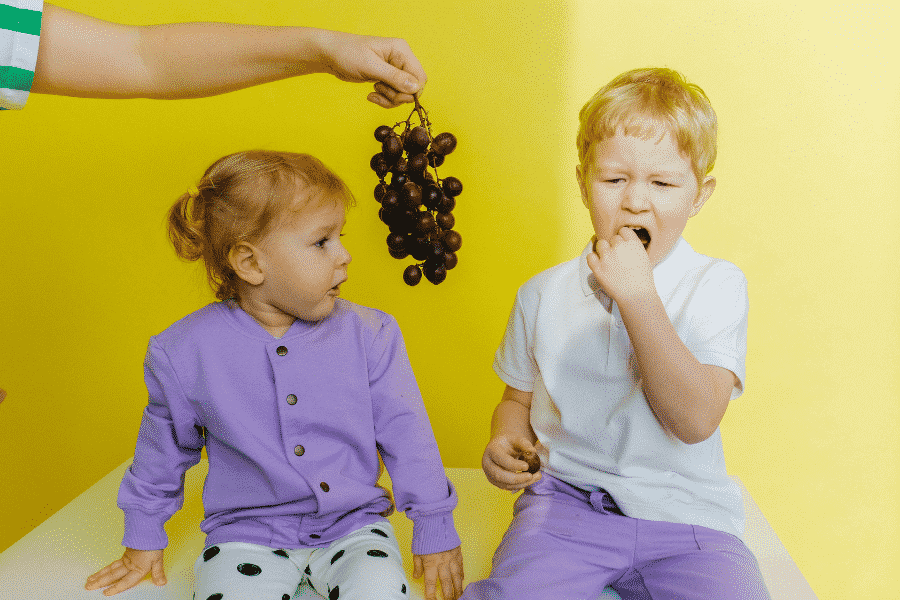 Dos niños comiendo uvas