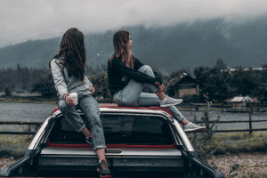 Dos chicas jóvenes encima de un coche